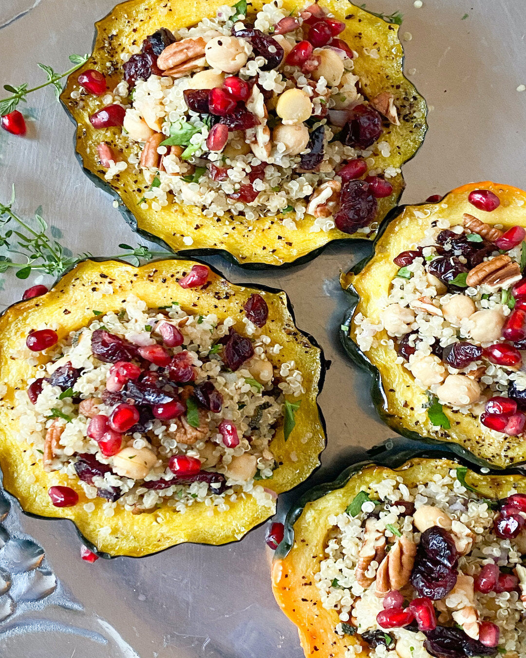 Beautiful stuffed acorn squash halves filled with quinoa, garbanzo beans, and topped with colorful pomegranate seeds