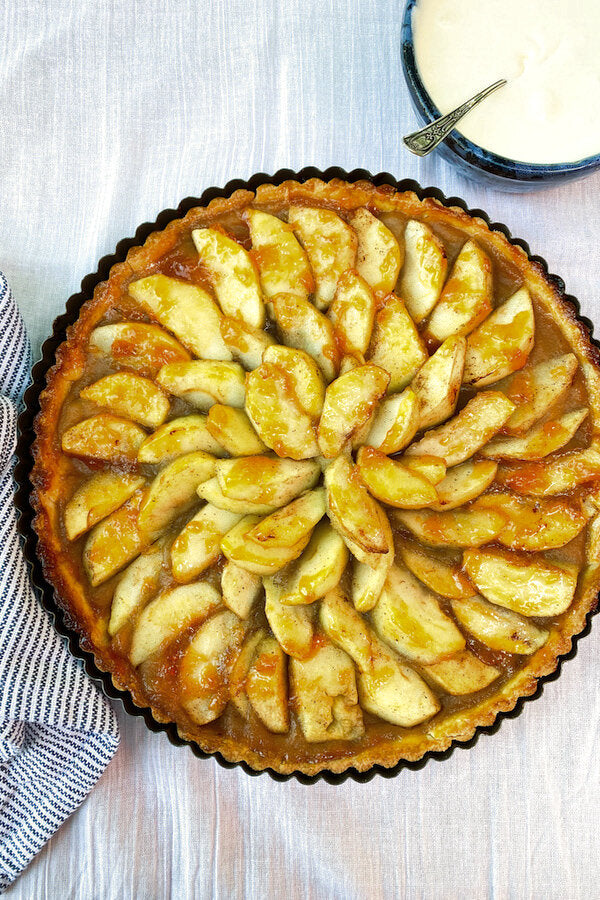 Elegant French apple tart with perfectly arranged apple slices in concentric circles, glazed with apricot and Calvados