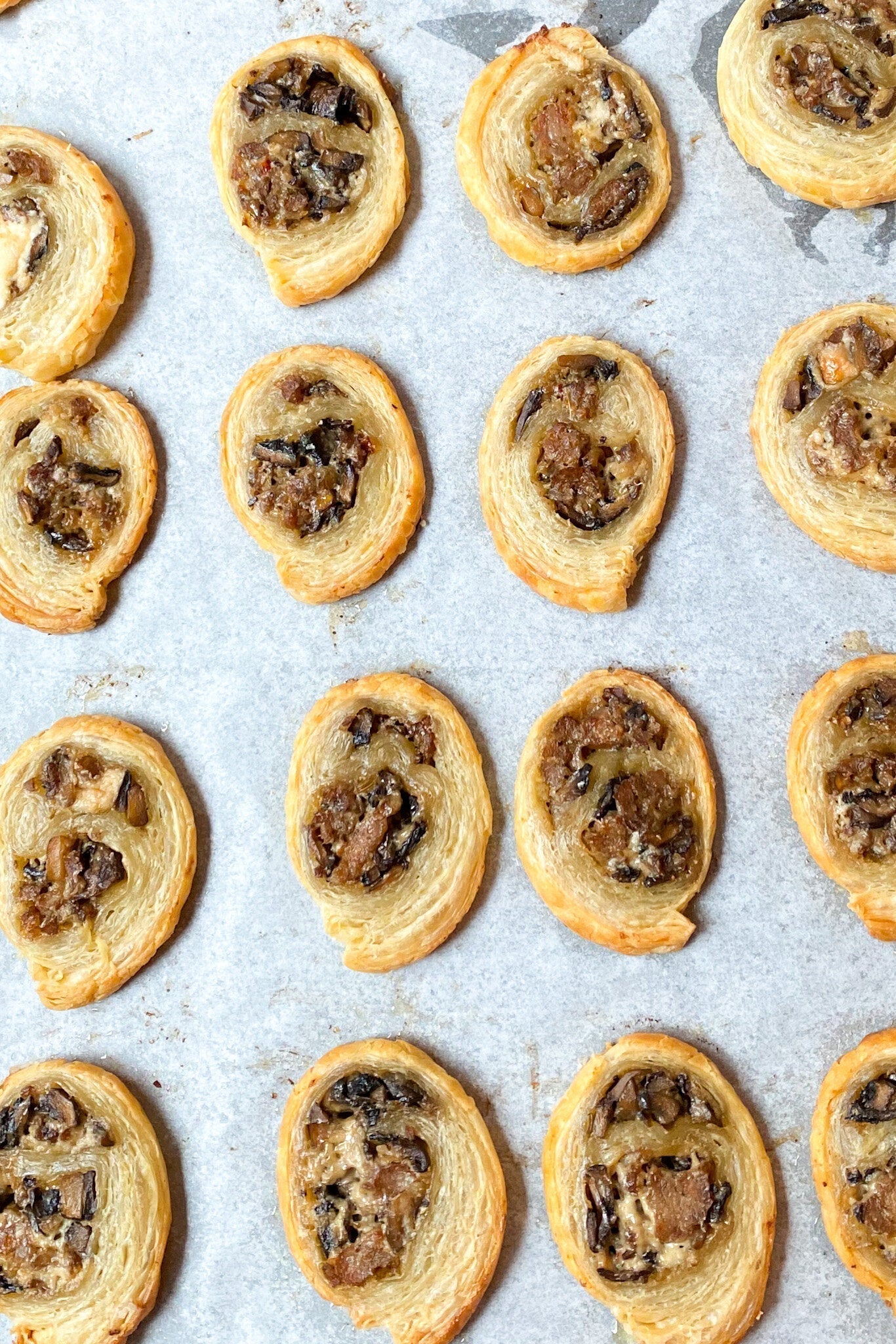 Golden brown sausage mushroom puff pastry appetizers arranged on a serving platter