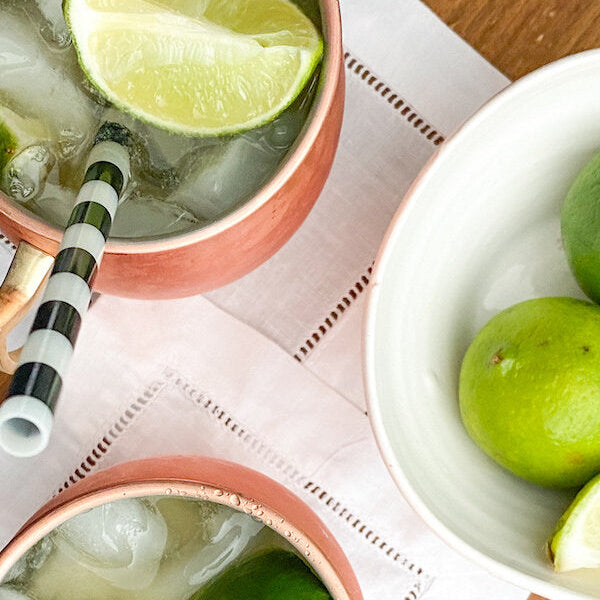 A Kentucky Mule cocktail served in a copper mug with fresh lime wedges and blackberries