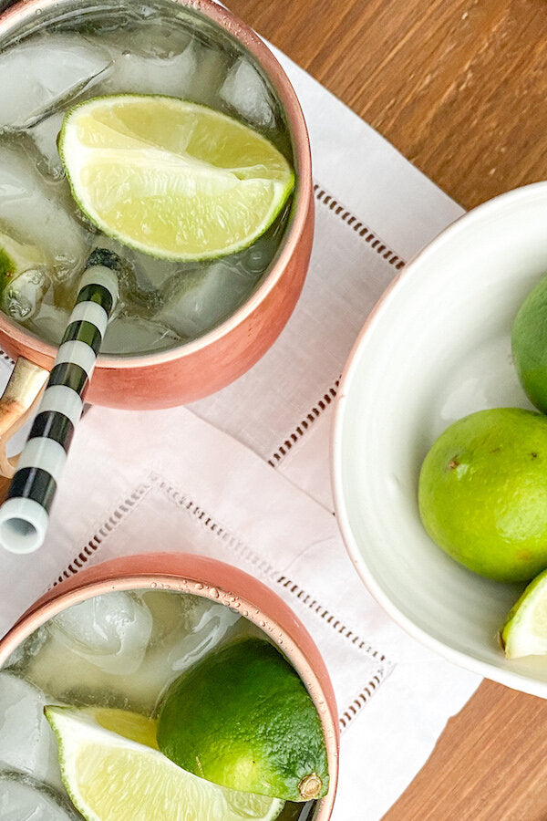 A Kentucky Mule cocktail served in a copper mug with fresh lime wedges and blackberries