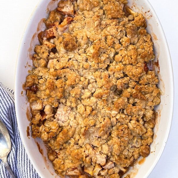 Golden brown apple bourbon crisp in a baking dish, with crispy oat topping and tender apples visible underneath