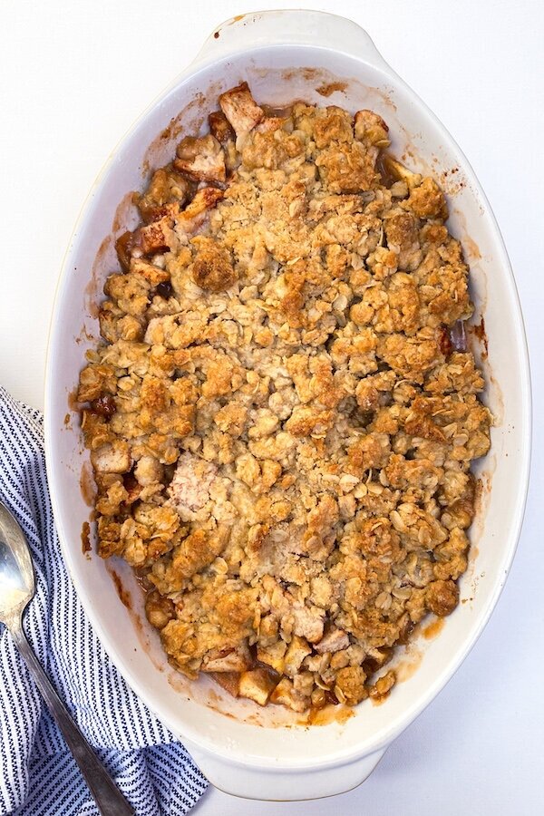 Golden brown apple bourbon crisp in a baking dish, with crispy oat topping and tender apples visible underneath