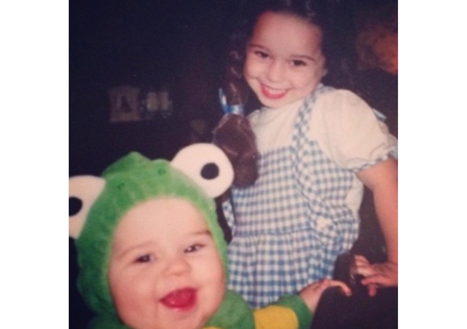 Two young girls in Halloween costumes - Lily dressed as a green frog and Haly wearing a Dorothy from Wizard of Oz costume with ruby slippers and blue dress