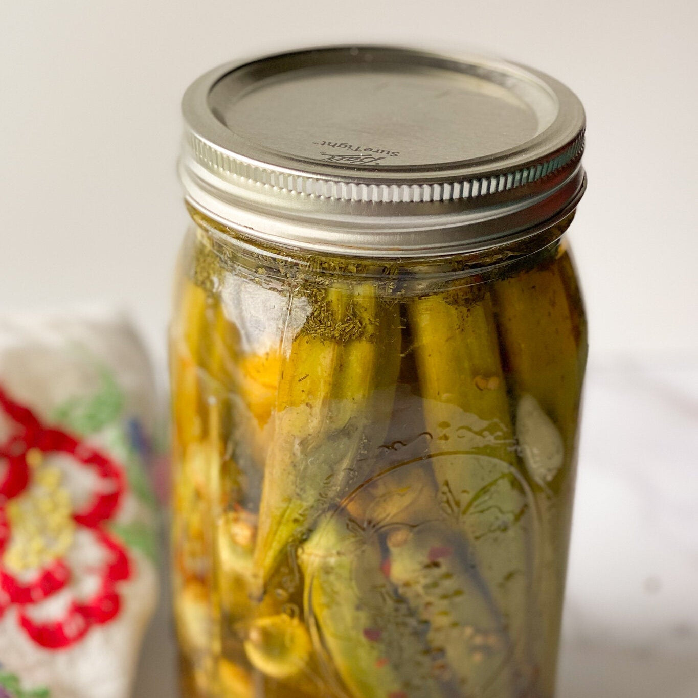 Jar of quick pickled okra with garlic and dill, ready to serve on a snack board