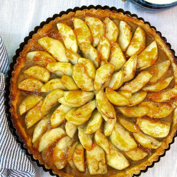 Elegant French apple tart with perfectly arranged apple slices in concentric circles, glazed with apricot and Calvados
