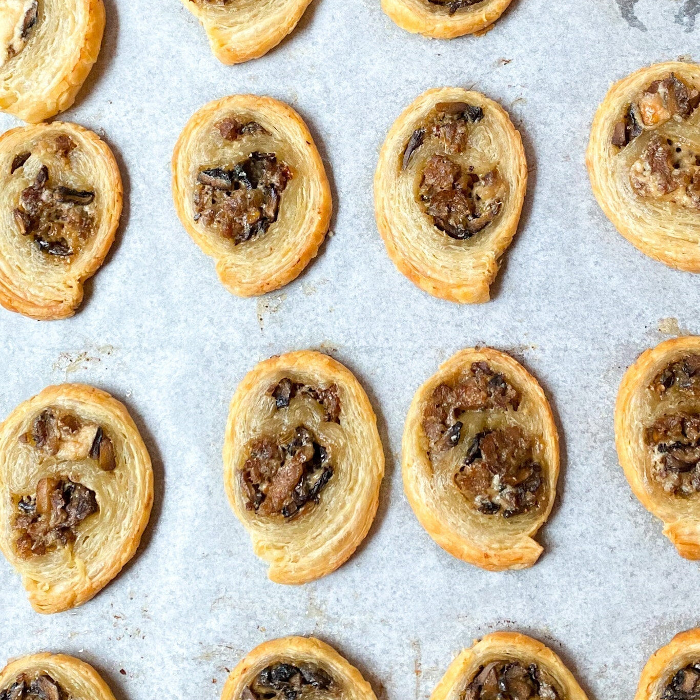 Golden brown sausage mushroom puff pastry appetizers arranged on a serving platter