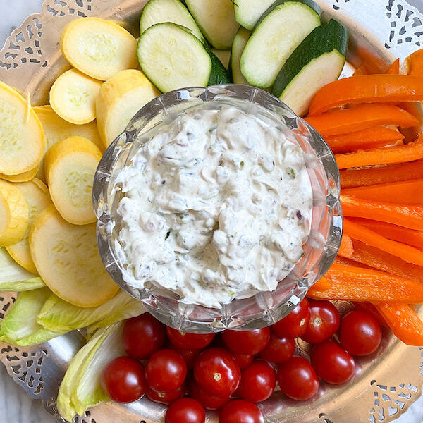 Creamy pistachio herb dip served in an elegant bowl with fresh vegetables on a silver tray