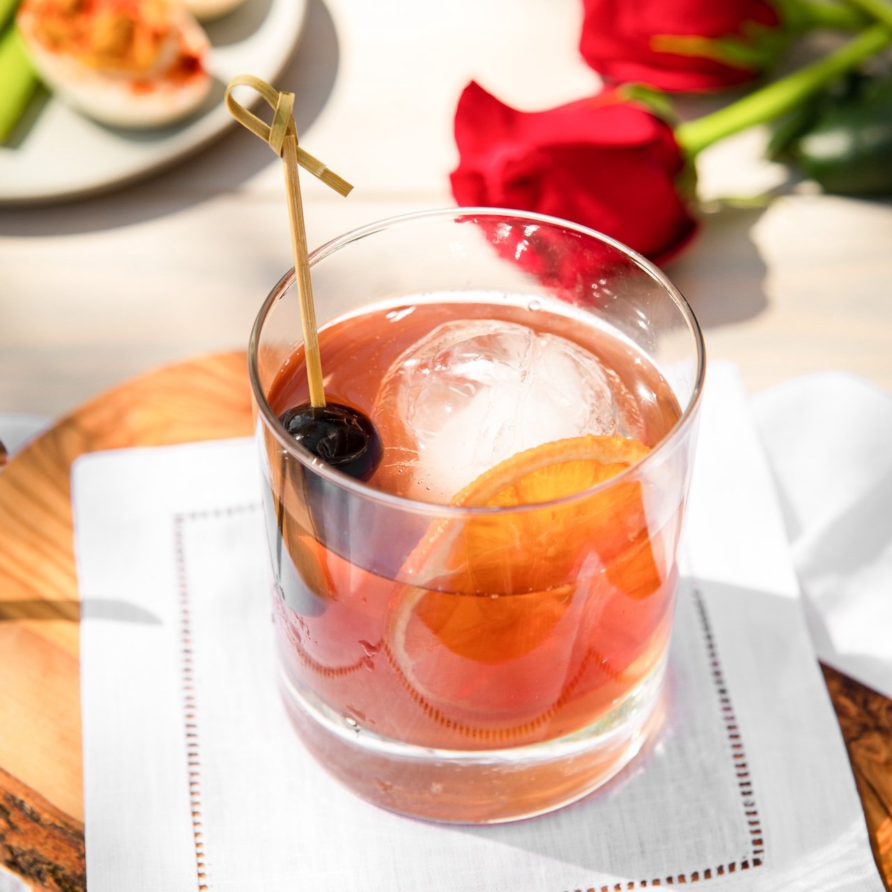Bourbon Old Fashioned cocktail served over ice with orange twist and cocktail cherries in a rocks glass.