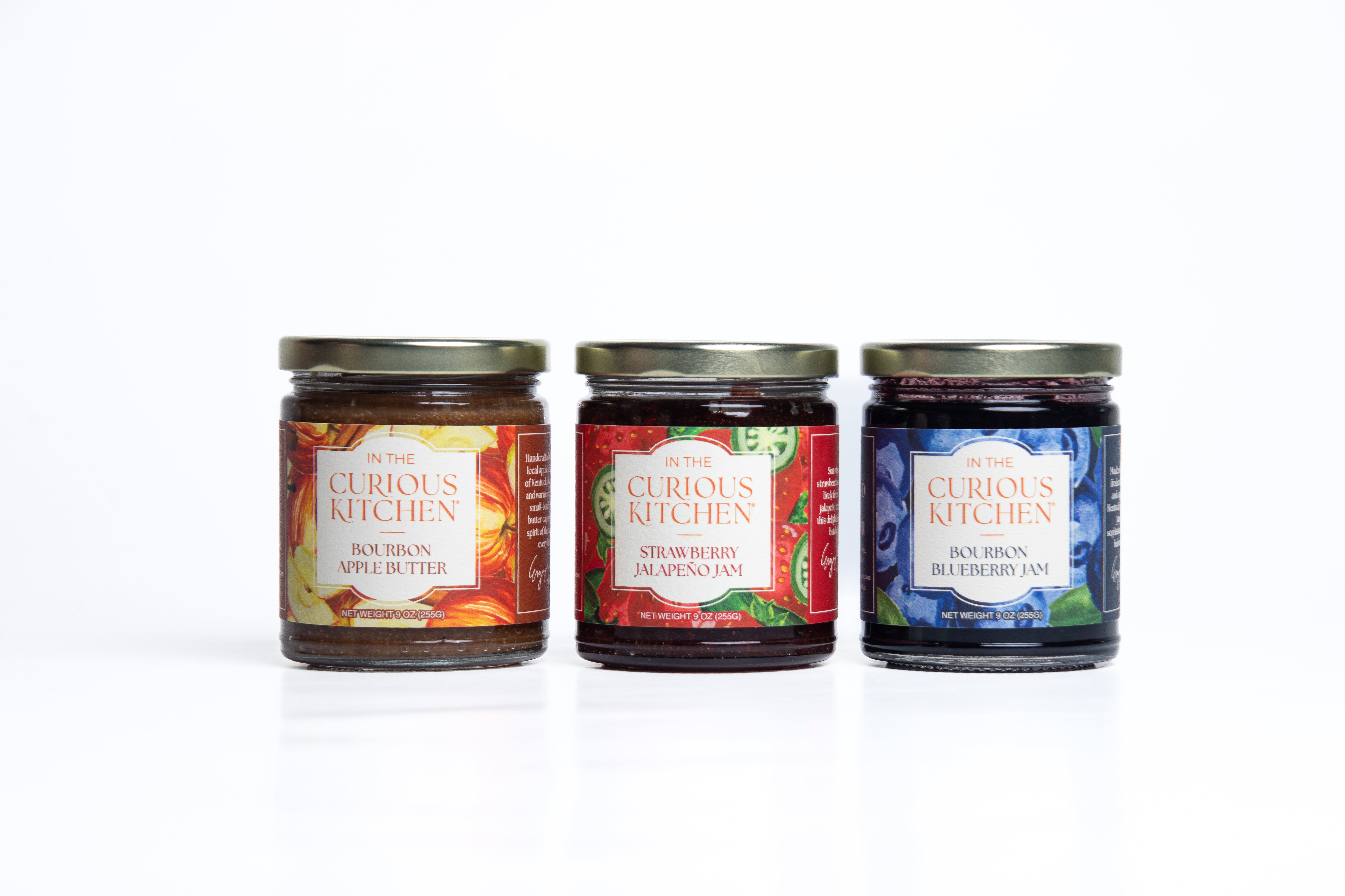 Three jars of Curious Kitchen jams on a white background