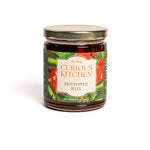 Jar of hot pepper jelly from 'In the Curious Kitchen' on a white background