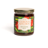 Jar of hot pepper jelly from 'In the Curious Kitchen' on a white background